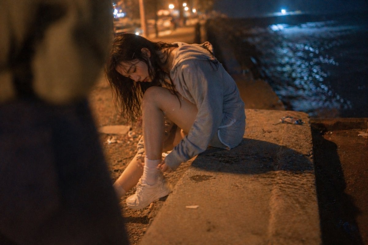 这是一条高细节提示词，用于生成电影感、手持拍摄风格的女性夜间海滩人像，包含逼真的皮肤纹理与光影效果。