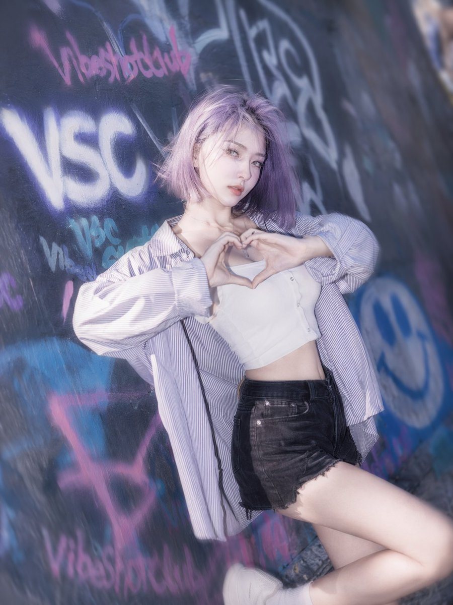 生成一张年轻女性身着街头服饰，以涂鸦墙为背景的写实人像。