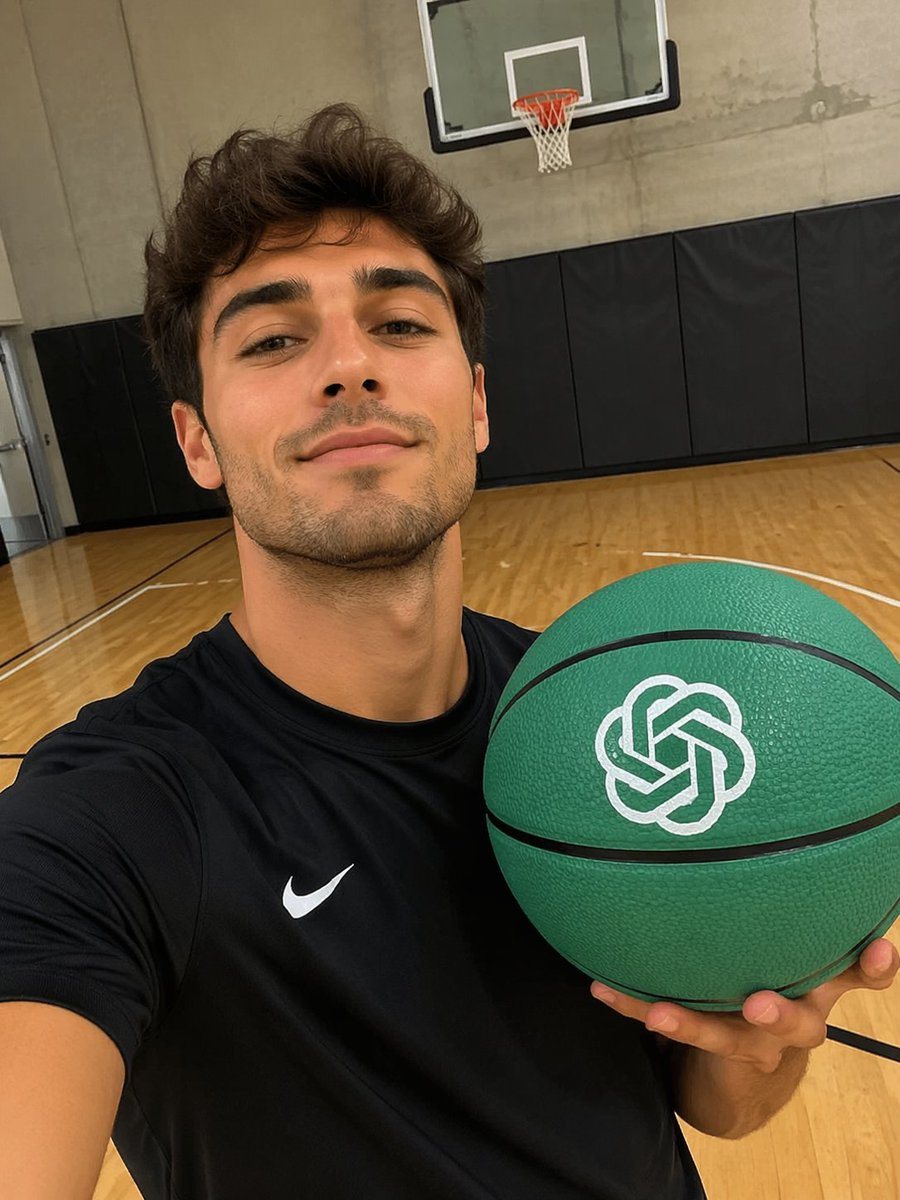 A photorealistic selfie of a young man with short wavy dark hair and light stubble on an indoor basketball court. He wears a black athletic t-shirt with a white swoosh. He holds a green b...