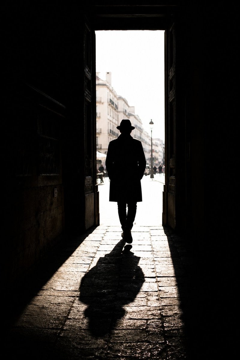 A prompt for street photography focusing on silhouettes, strong directional sunlight, and cinematic urban composition.