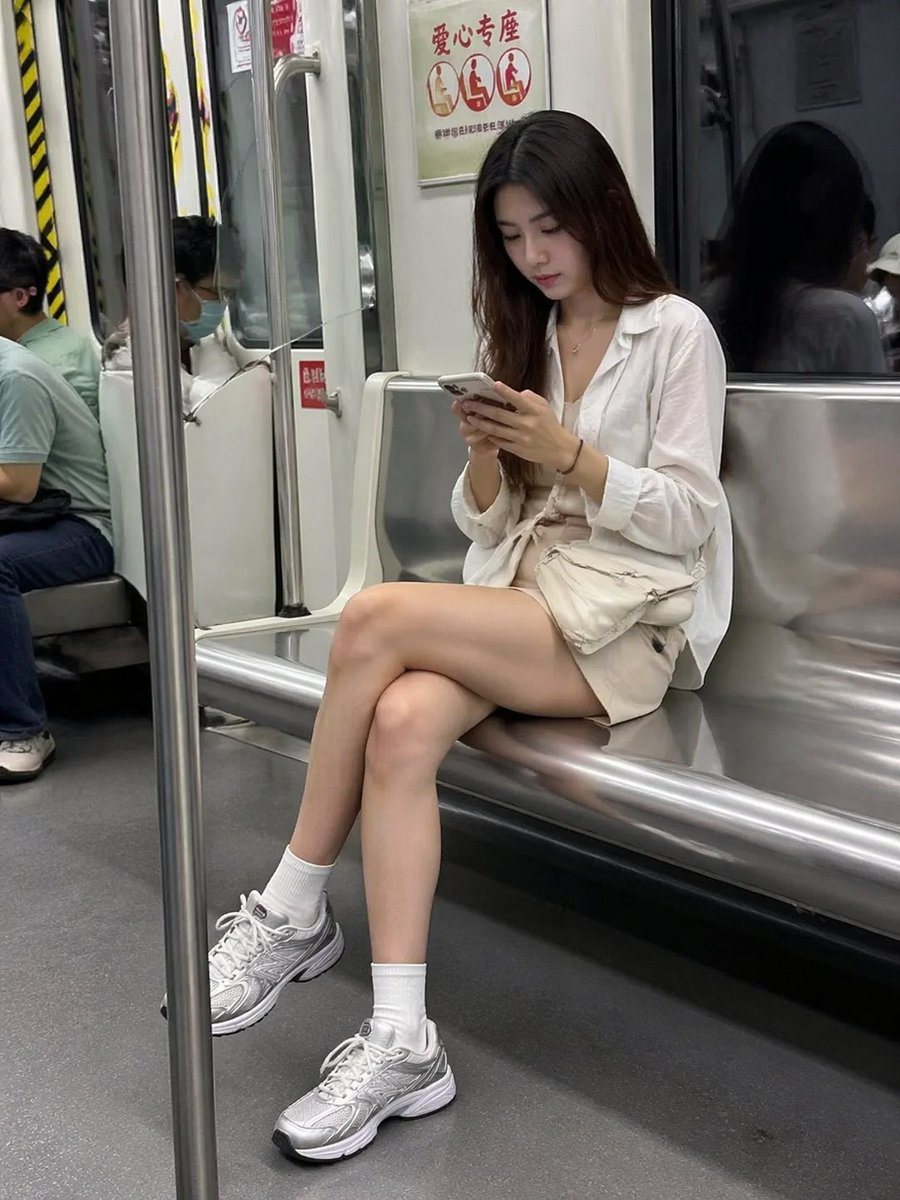 一个用于生成地铁上女性低头看手机的抓拍风格照片的真实感提示词。