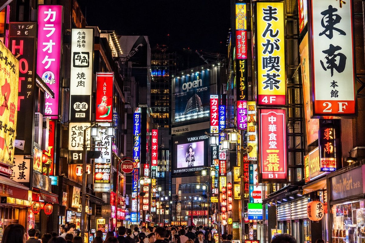 A photorealistic night street photography shot of a bustling Tokyo street, heavily illuminated by densely packed vertical neon signs and billboards. On the left, a bright pink sign promin...