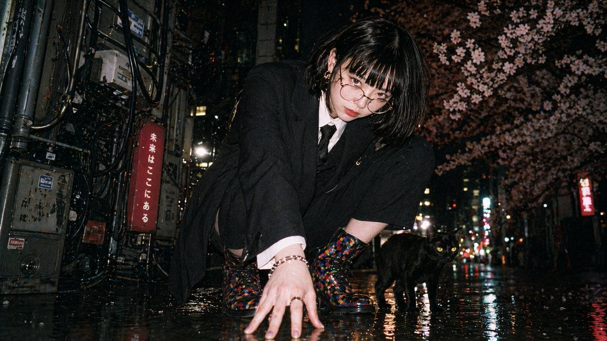 This prompt generates a gritty low-angle nighttime street portrait with direct-flash film-camera vibes, ideal for recreating candid Japanese urban fashion photography.