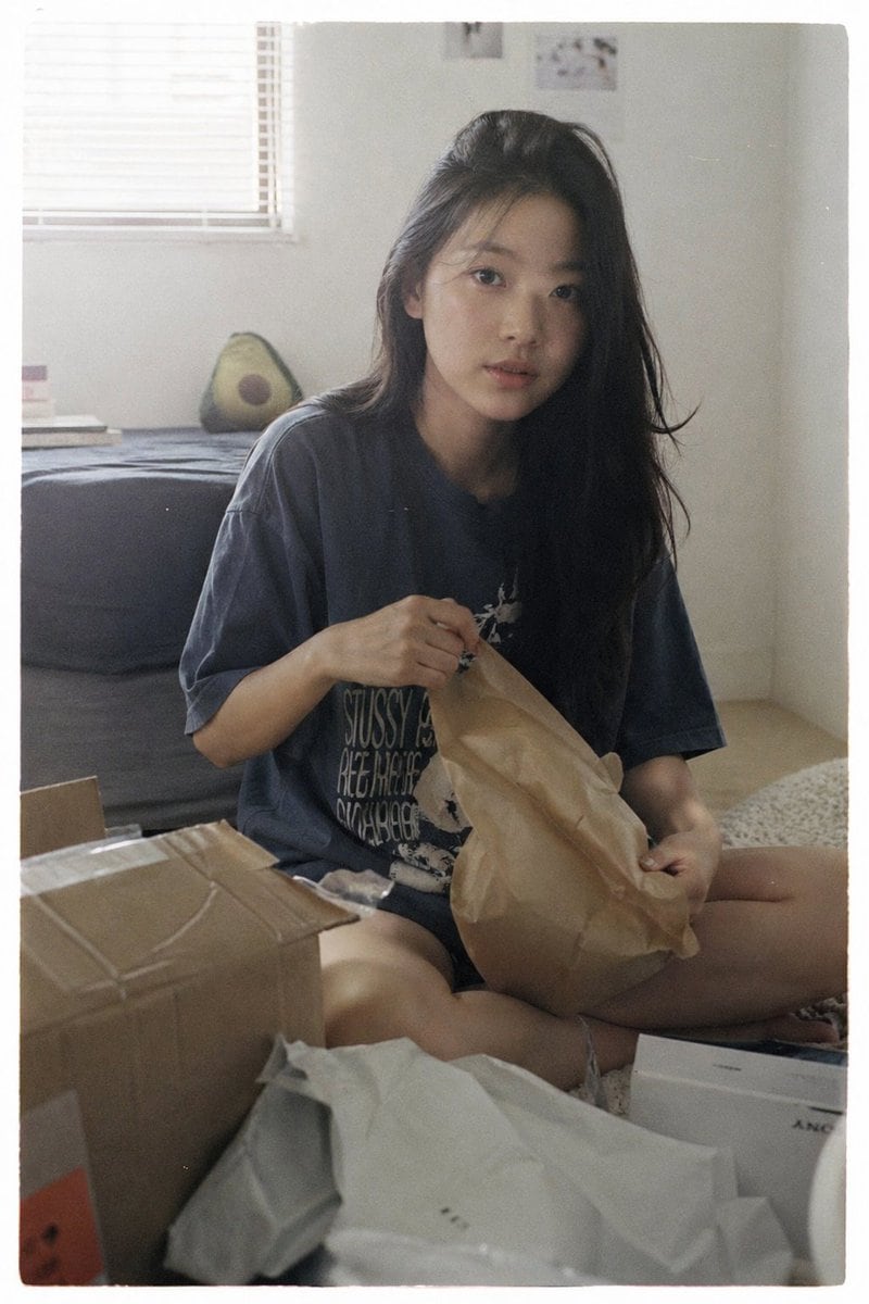 Japanese negative film aesthetic, unboxing moment, soft natural light, slight highlight bloom, low contrast, muted colors, subtle grain subject sitting on floor or bed, opening a package,...