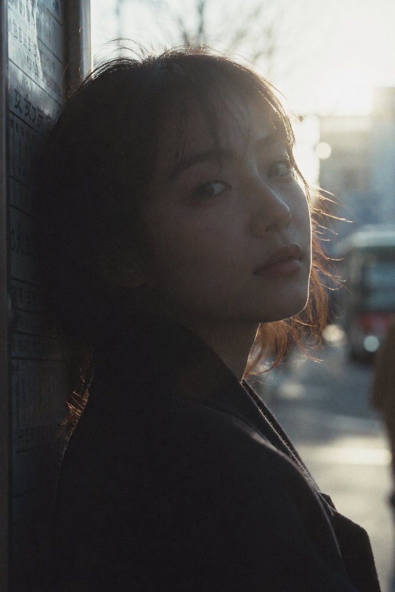 Japanese negative film aesthetic, close-up street silhouette portrait at bus stop, tight framing, head-and-shoulder composition, subject positioned very close to camera, soft but directio...